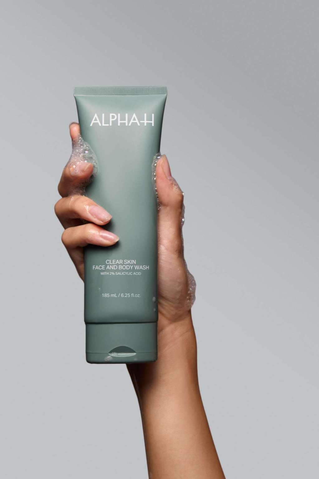 Alpha-H Clear Skin Face & Body Wash tubo en la mano