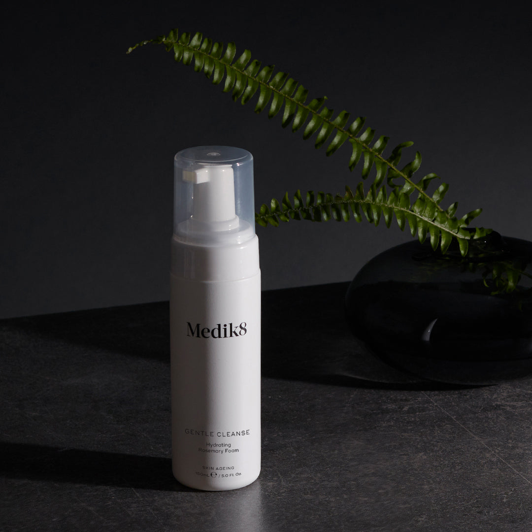Medik8 Gentle Cleanse frasco sobre fondo oscuro con helecho