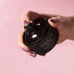 Oolaboo Blushy Truffle Sparkling Oil dosificador con gota de aceite en la mano