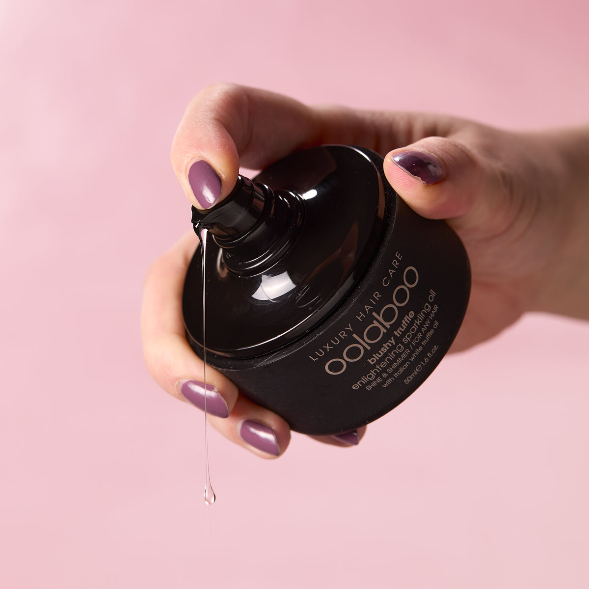 Oolaboo Blushy Truffle Sparkling Oil dosificador con gota de aceite en la mano