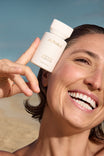 Alpha-H Liquid Gold Exfoliating Treatment modelo con el frasco junto al mar