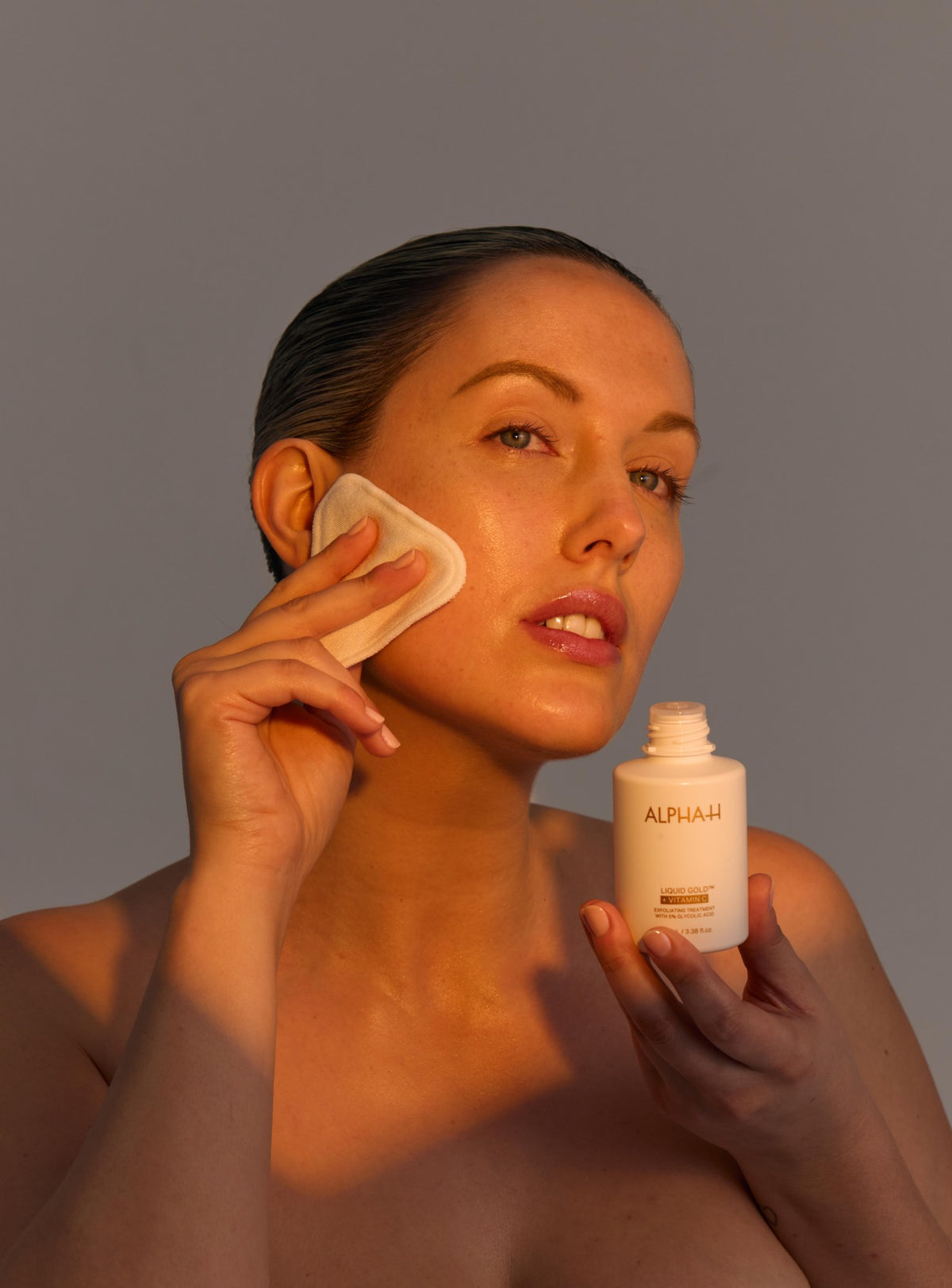 Alpha-H Liquid Gold + Vitamin C Exfoliating Treatment modelo con disco de algodón