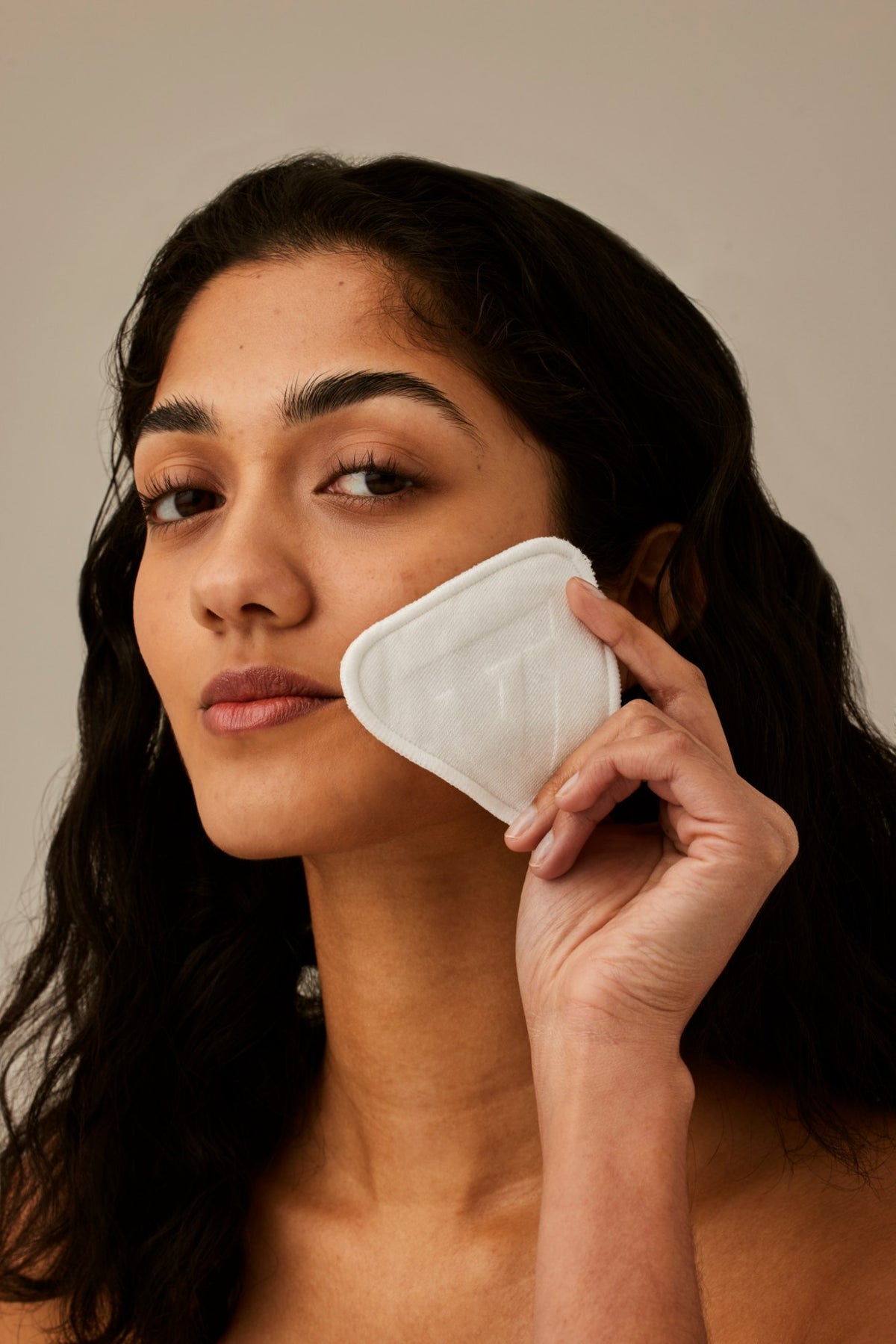 Alpha-H Re-usable Bamboo Cotton Pads modelo con disco junto al rostro