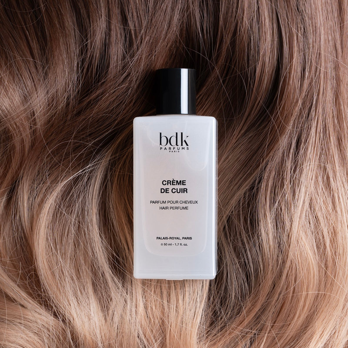 BDK Parfums Hair Perfume Creme de Cuir frasco sobre cabello castaño rubio