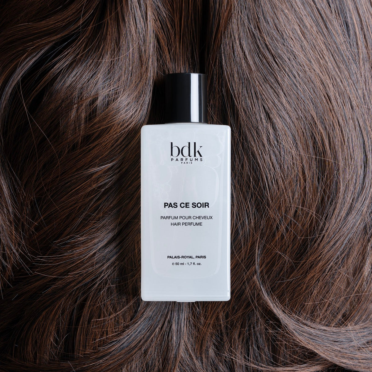 BDK Parfums Hair Perfume Pas Ce Soir frasco sobre cabello castaño oscuro