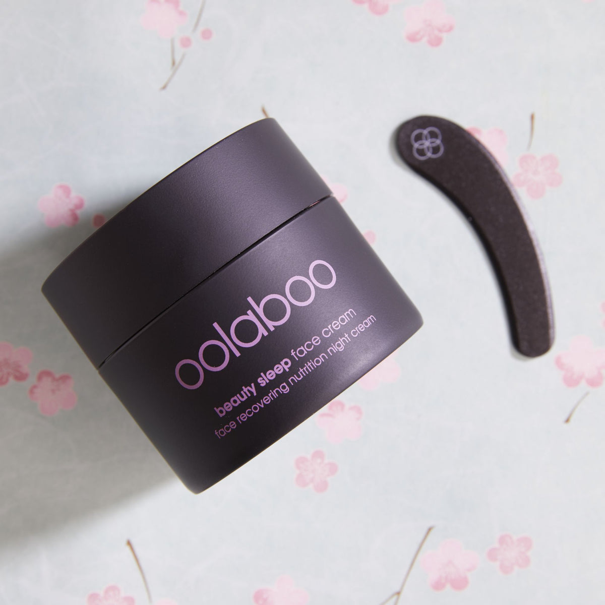 Oolaboo Beauty Sleep Night Cream con espátula sobre flores