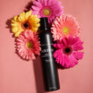 Oolaboo Glam Former Dry Shampoo entre gerberas rosas