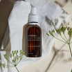 Oolaboo Super Foodies Matcha Infused Oil sobre paño de lino con flores