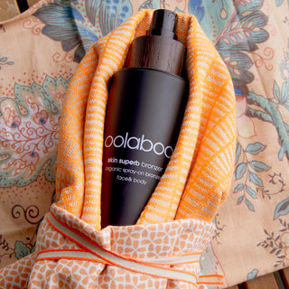 Oolaboo Skin Superb Organic Spray-on Bronzer en un paño naranja
