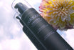 Oolaboo Straight Baobab Shampoo contra un cielo nublado con dalia