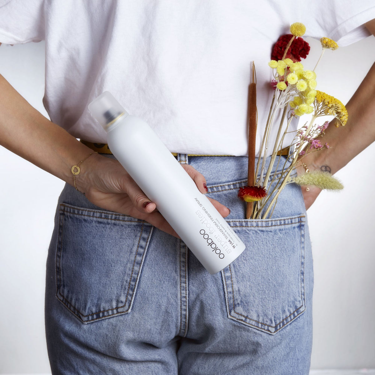 Oolaboo Super Foodies Transform Finishing Spray en un bolsillo trasero con flores